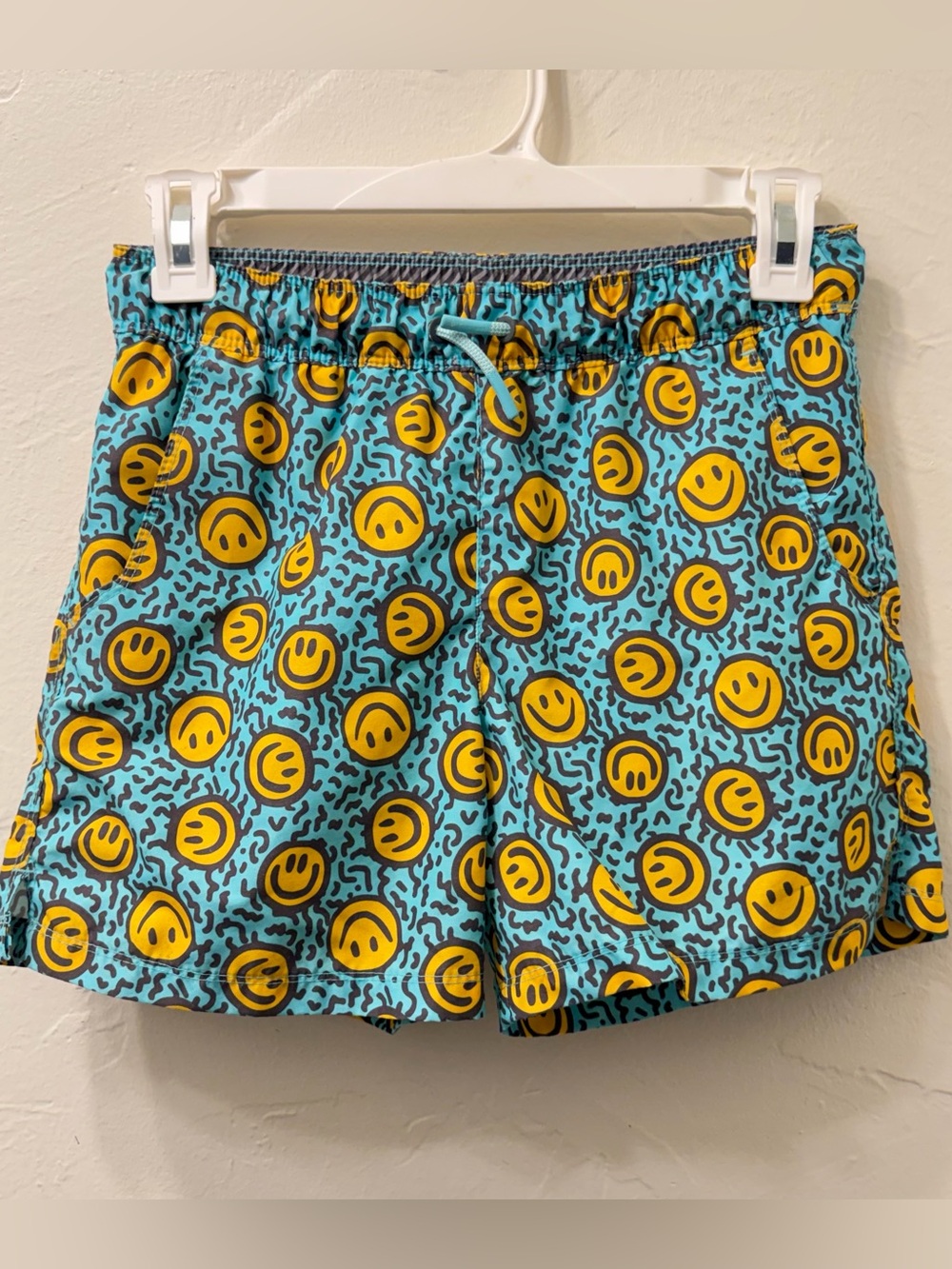 Boys smiley face swim trunks on blue background with black speckles, size 6